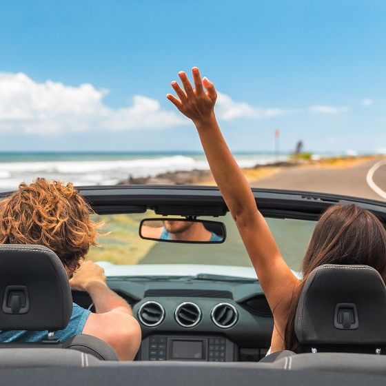 Ein Paar fährt im Auto an einer Küstenstraße